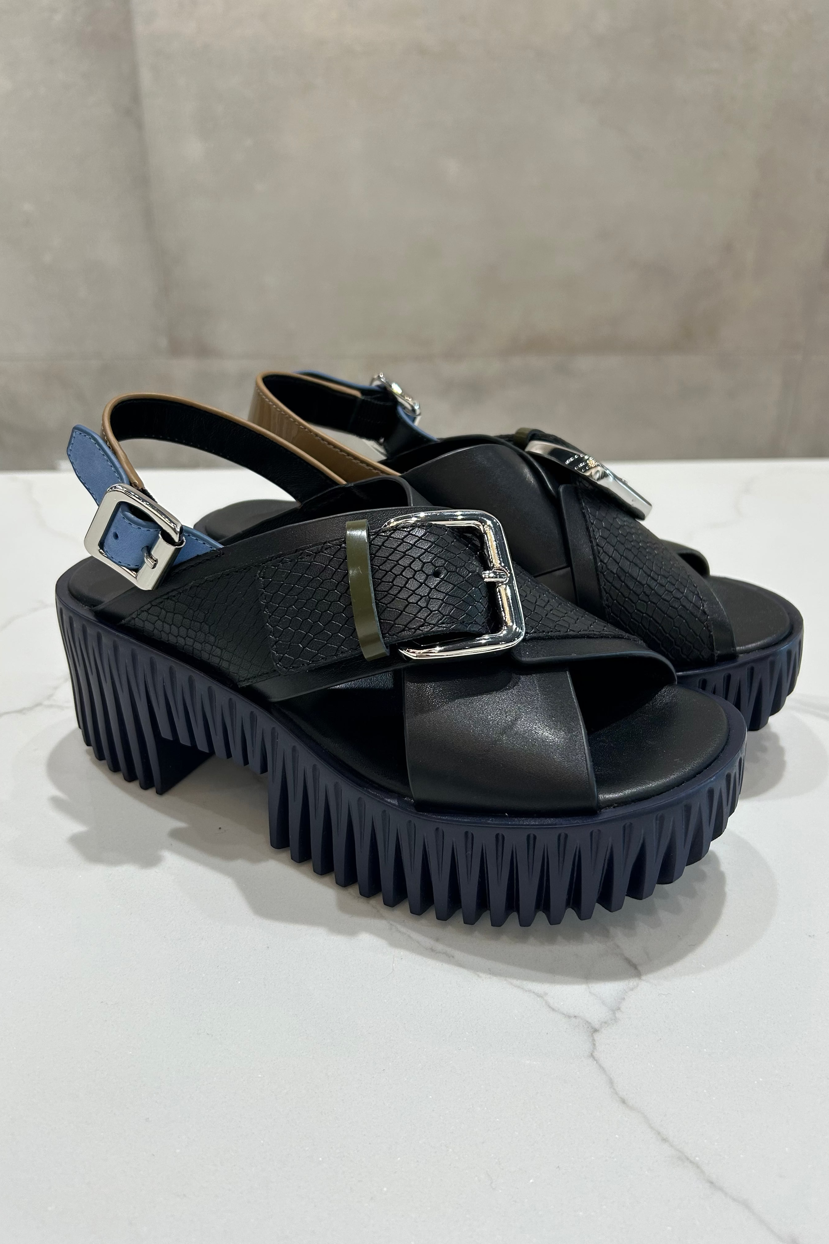 Black platform sandals with thick soles on a light surface