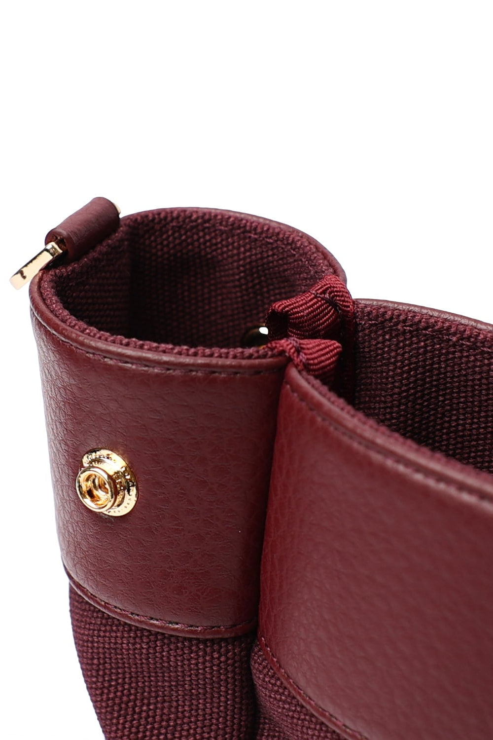 Close-up of a burgundy two-tone tote bag showing its textured canvas lining, synthetic leather trim, and gold-tone snap button.